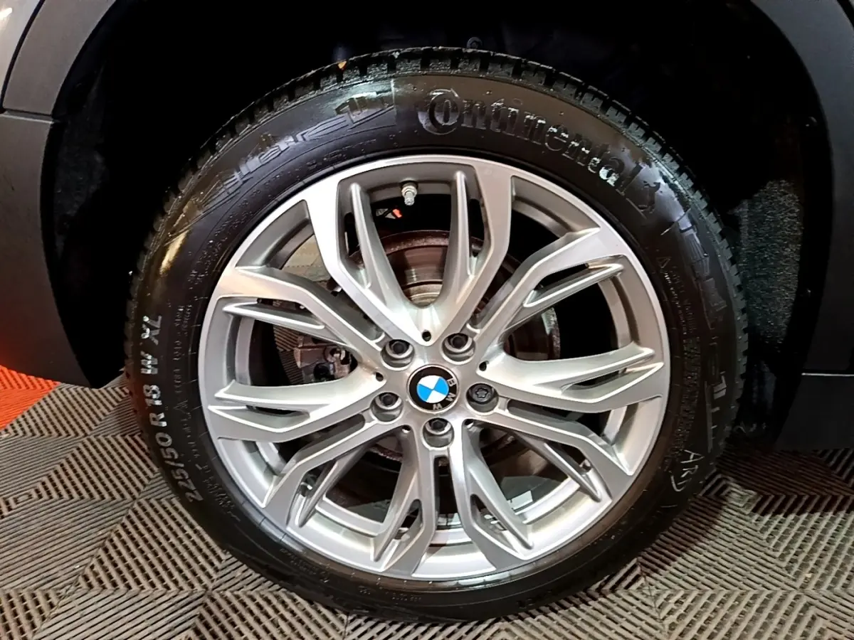 Gros plan sur la roue arrière droite d’un BMW X2 gris foncé, mettant en valeur le pneu Continental et l’arche de roue.