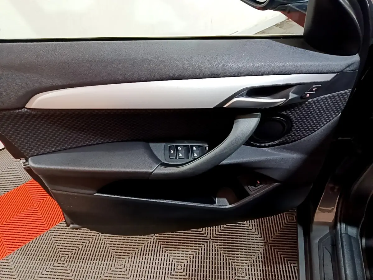 Vue intérieure du panneau de porte avant gauche gris foncé de la BMW X2 sDrive18i Lounge DKG7 2021 avec commandes électriques.