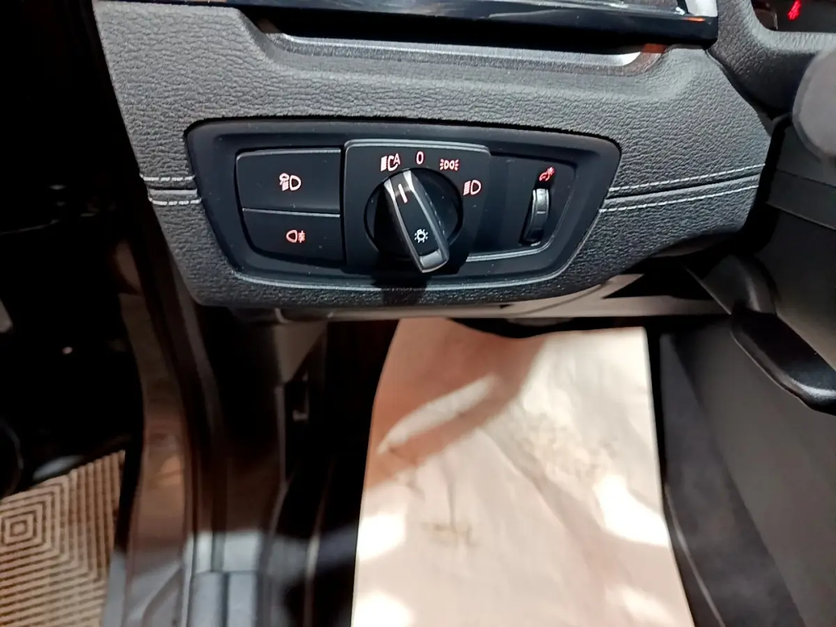 Gros plan sur le bouton de commande des phares dans l'habitacle d'une BMW X2 gris foncé, côté conducteur.