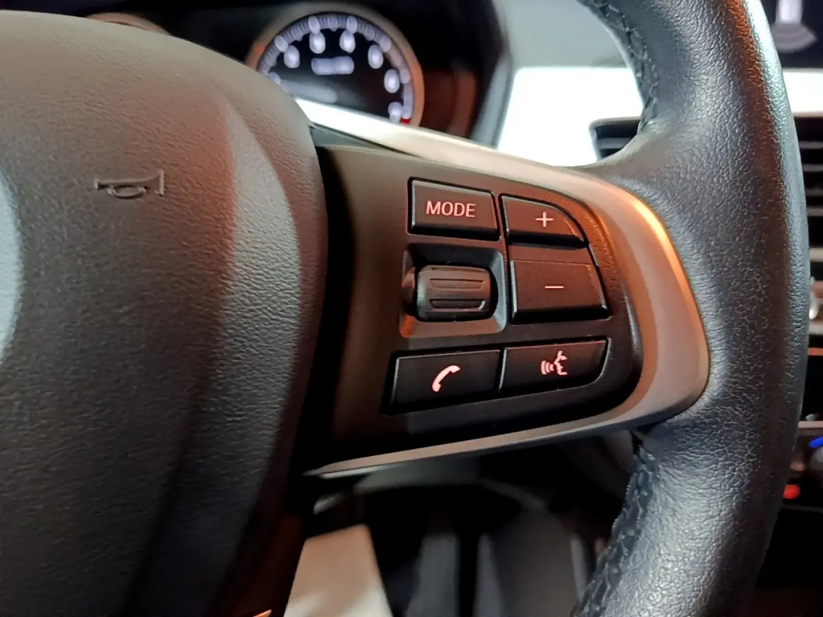 Gros plan sur les commandes multimédias au volant cuir noir du BMW X2 sDrive18i Lounge 2021.