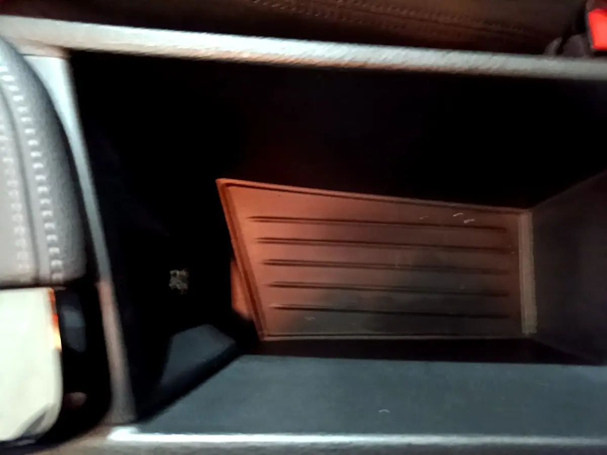 Intérieur du rangement central de la BMW X2 sDrive18i Lounge DKG7, vue plongeante sur le compartiment noir.