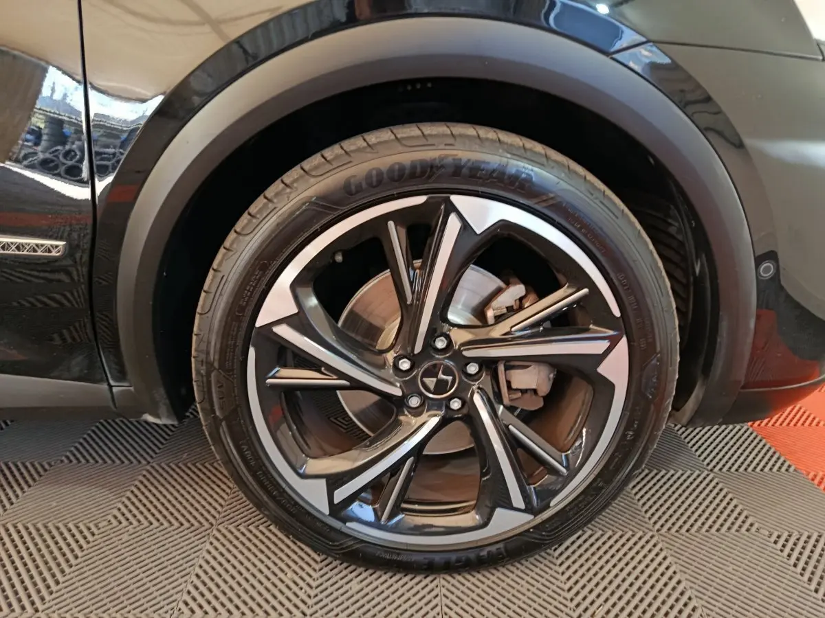 Gros plan sur la roue avant droite noire du DS7 Crossback E-TENSE 4x4 300 LOUVRE avec jante alliage bicolore.