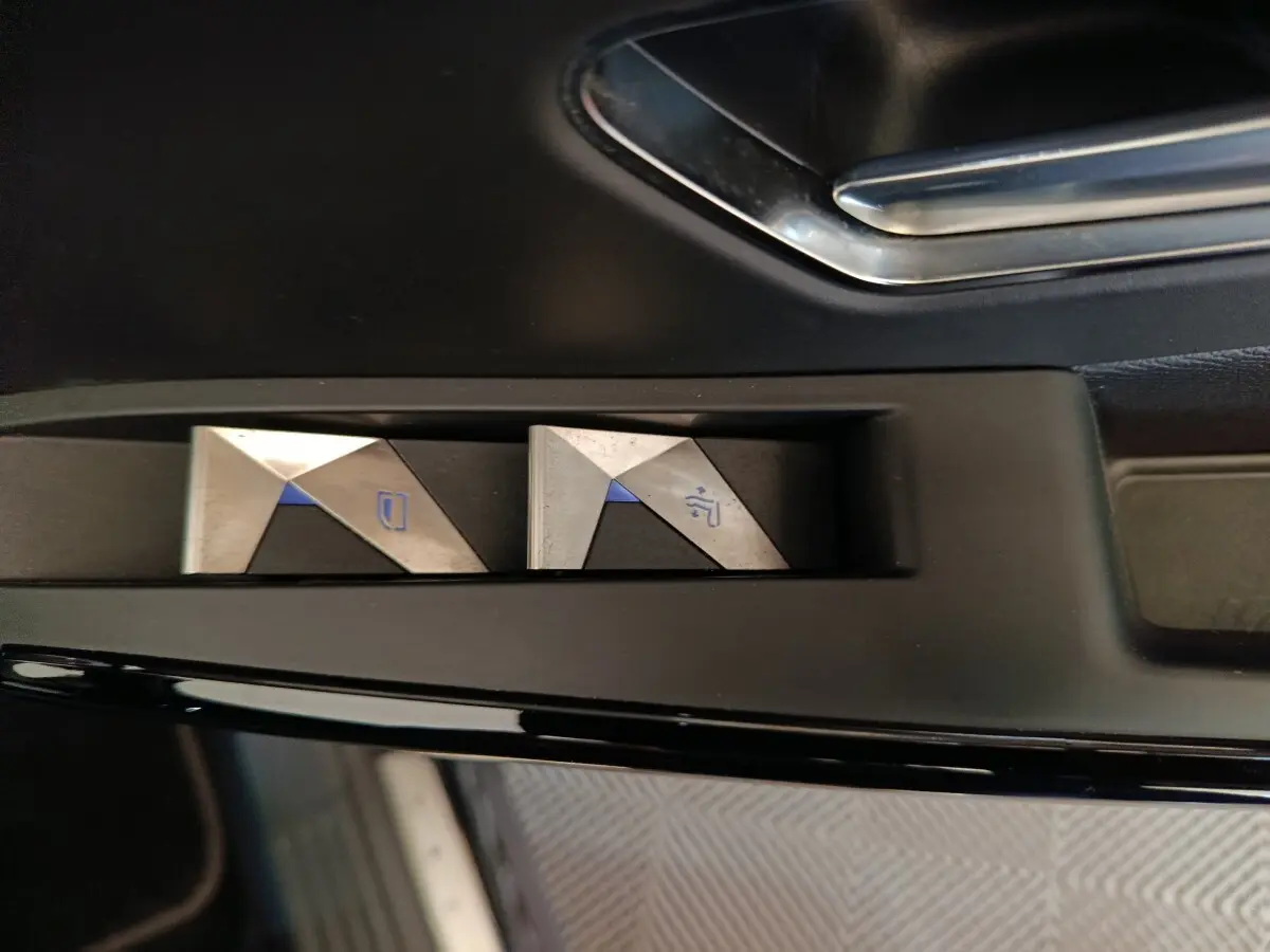 Gros plan sur les commandes de lève-vitres en métal brossé à l'intérieur d'une DS7 Crossback noir.
