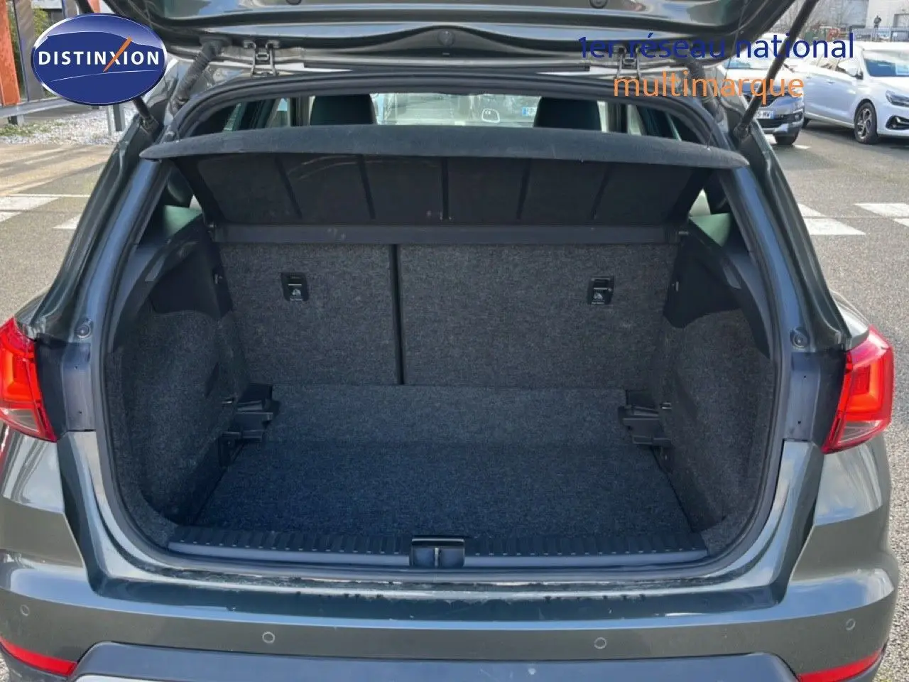 Coffre ouvert vu de l'arrière d'un SEAT Arona gris magnétique, montrant l'espace de chargement vide et la tablette cache-bagages.