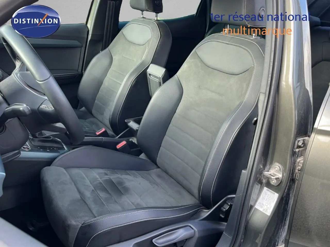 Vue intérieure côté conducteur du SEAT Arona gris métallique, sièges en cuir et alcantara avec surpiqûres blanches.
