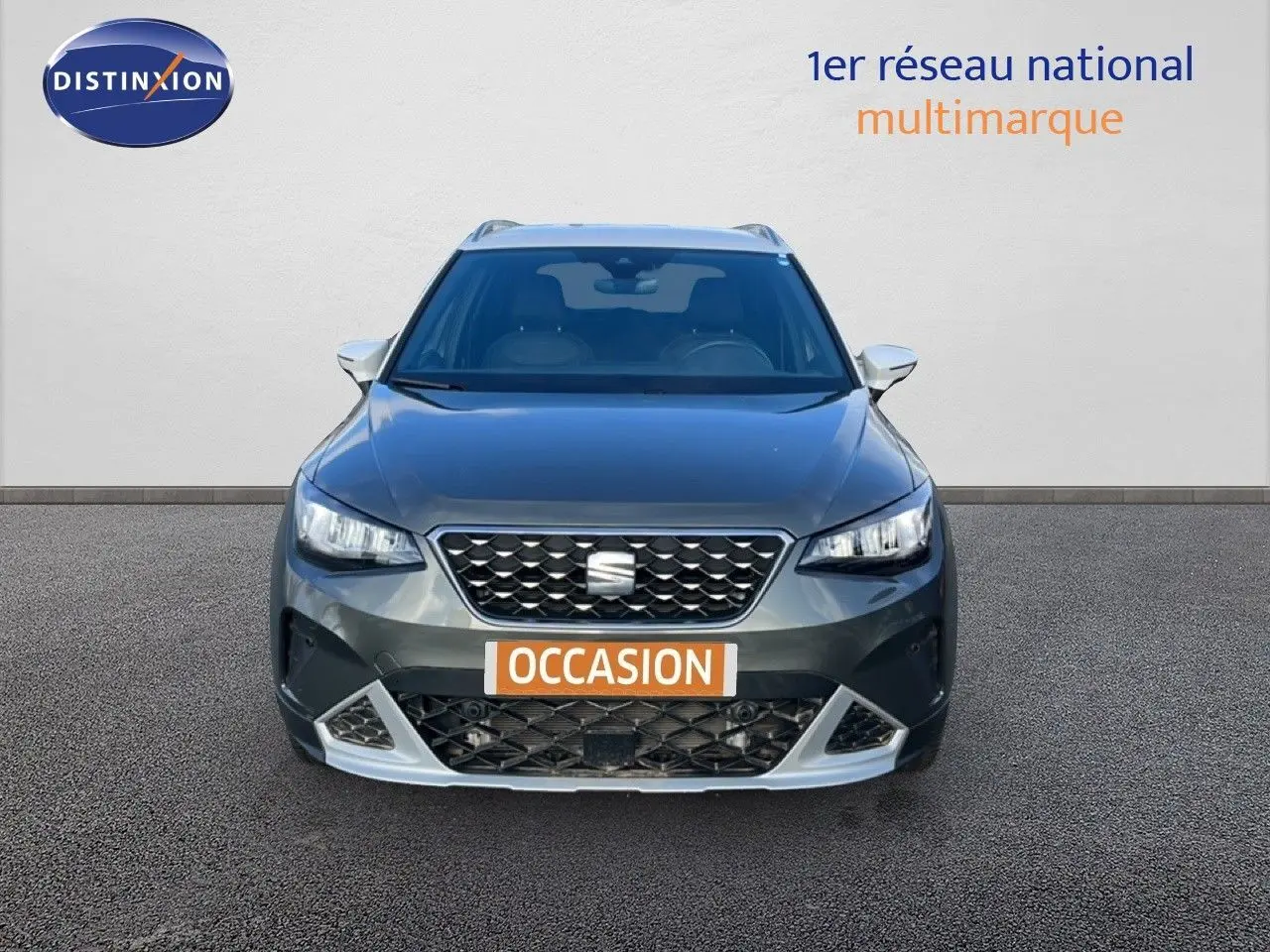 Vue frontale d'un SEAT Arona gris magnétique avec calandre noire et détails argentés, sur fond neutre.