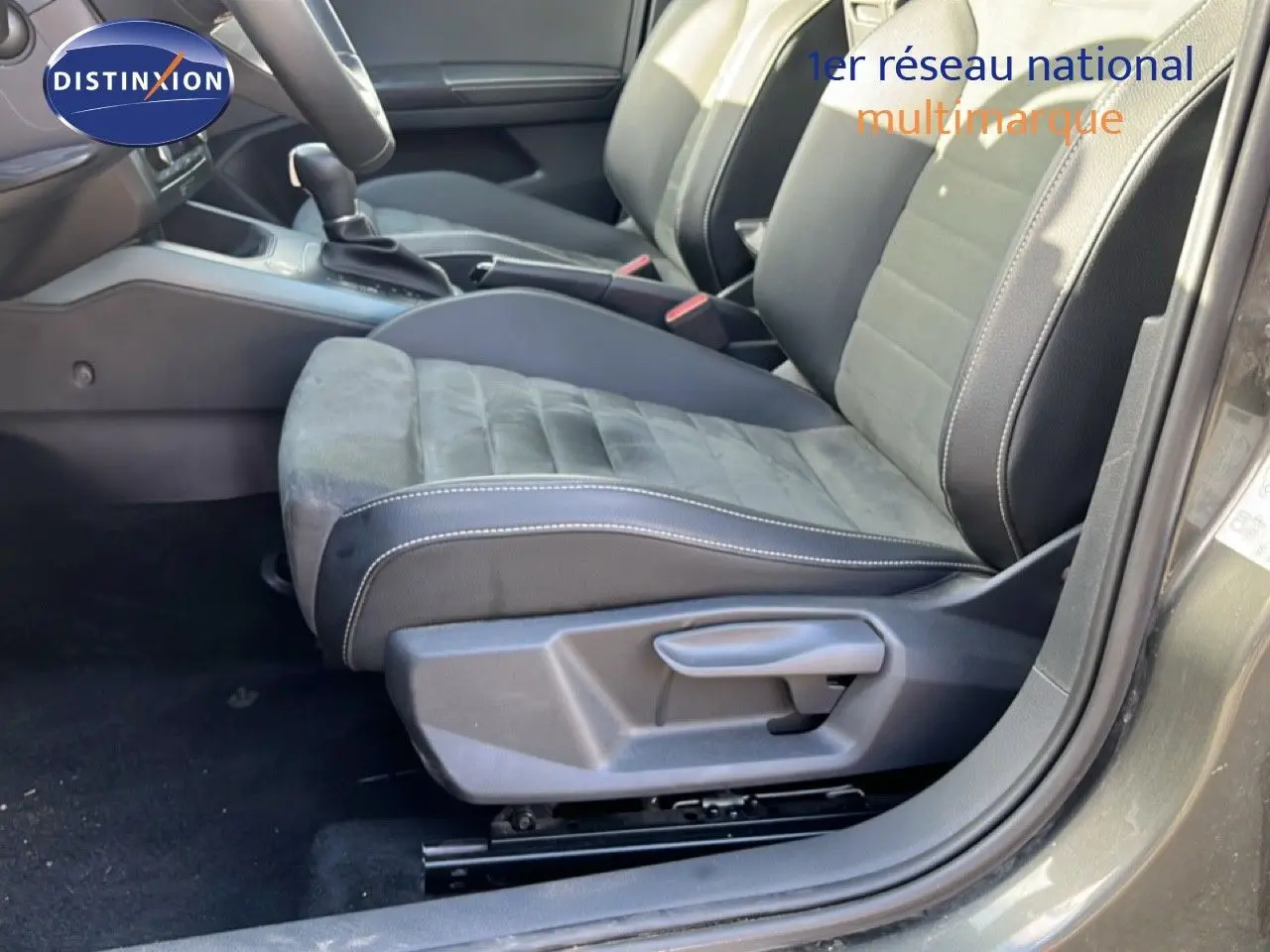 Vue intérieure côté conducteur du SEAT Arona 2025, sièges en tissu et cuir noir avec surpiqûres blanches.