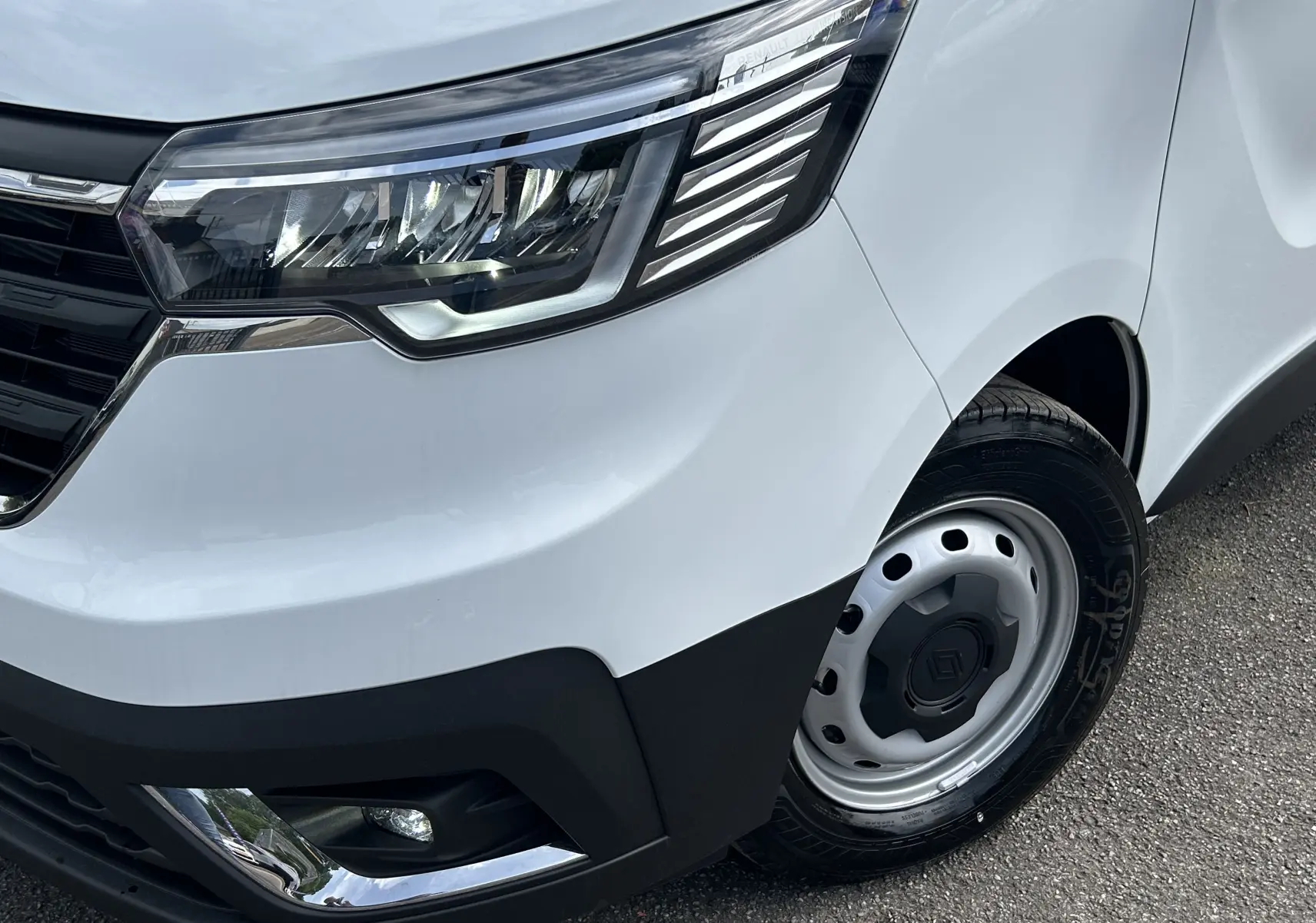 Gros plan sur l'avant droit blanc du Renault Trafic Fourgon avec phare LED et jante acier noire.