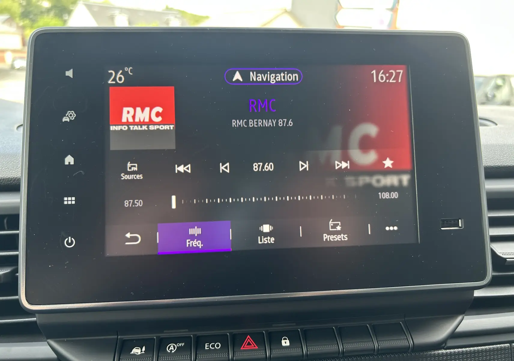 Écran tactile central du Renault Trafic blanc montrant la radio RMC à 87.6 FM avec commandes en bas.