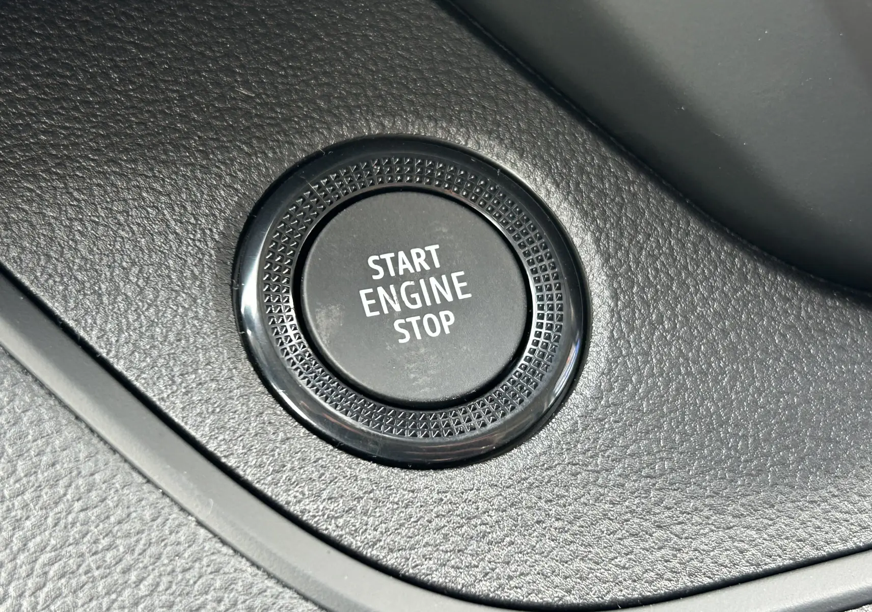 Gros plan sur le bouton Start Engine Stop noir intégré dans la console intérieure du Renault Trafic Fourgon blanc.
