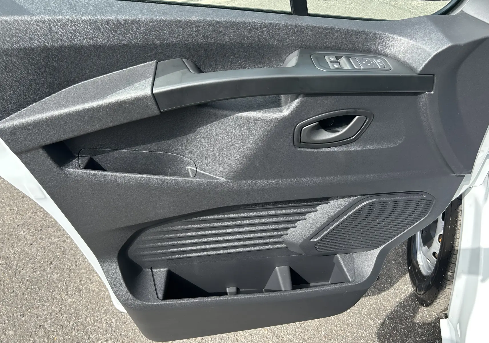 Vue rapprochée de la porte avant droite blanche du Renault Trafic Fourgon avec commandes de vitres et haut-parleur intégré.