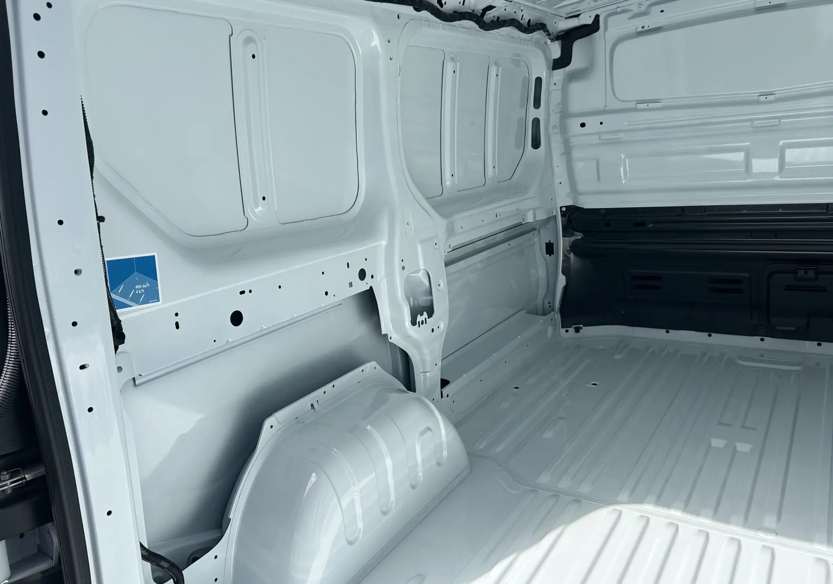 Vue intérieure côté gauche du coffre blanc du Renault Trafic Fourgon L1H1, montrant la cloison tôlée et l’espace de chargement.