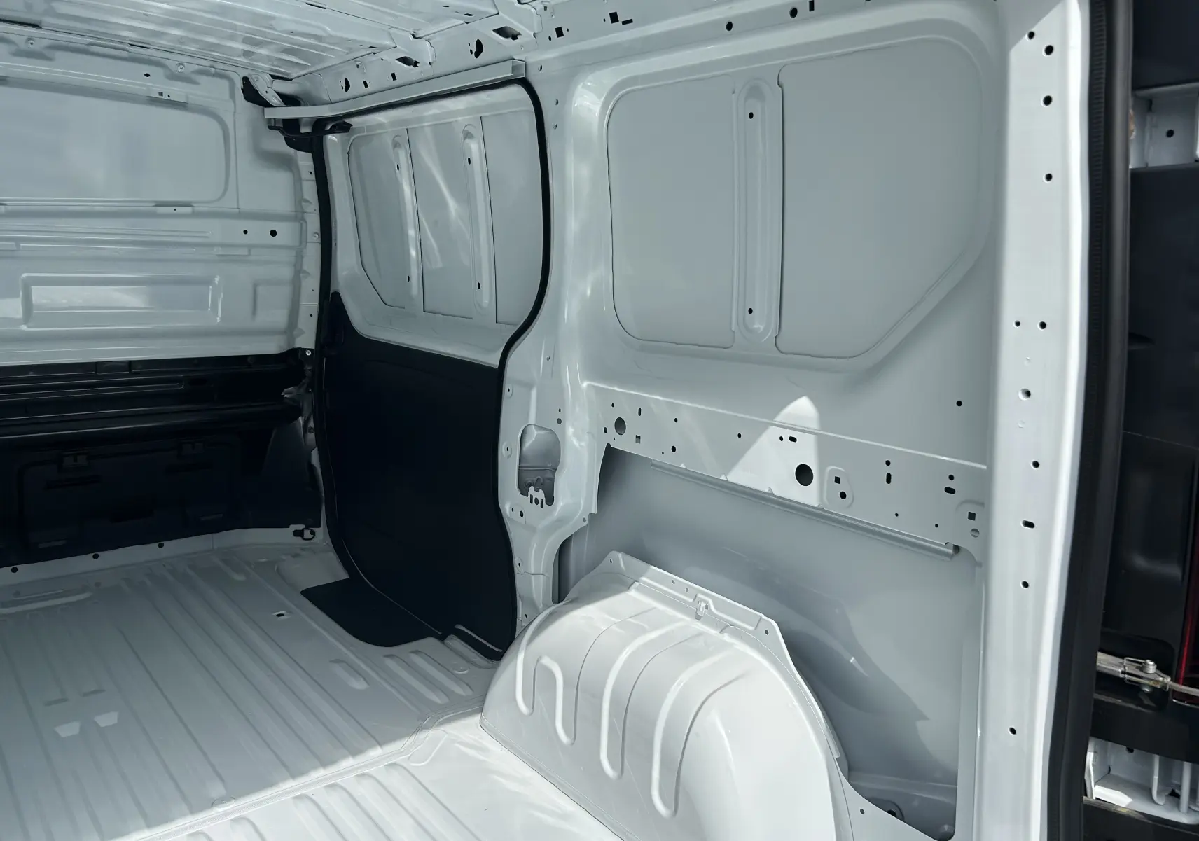 Intérieur du fourgon Renault Trafic blanc vu de l’arrière, montrant la cloison complète tôlée et l’espace de chargement vide.