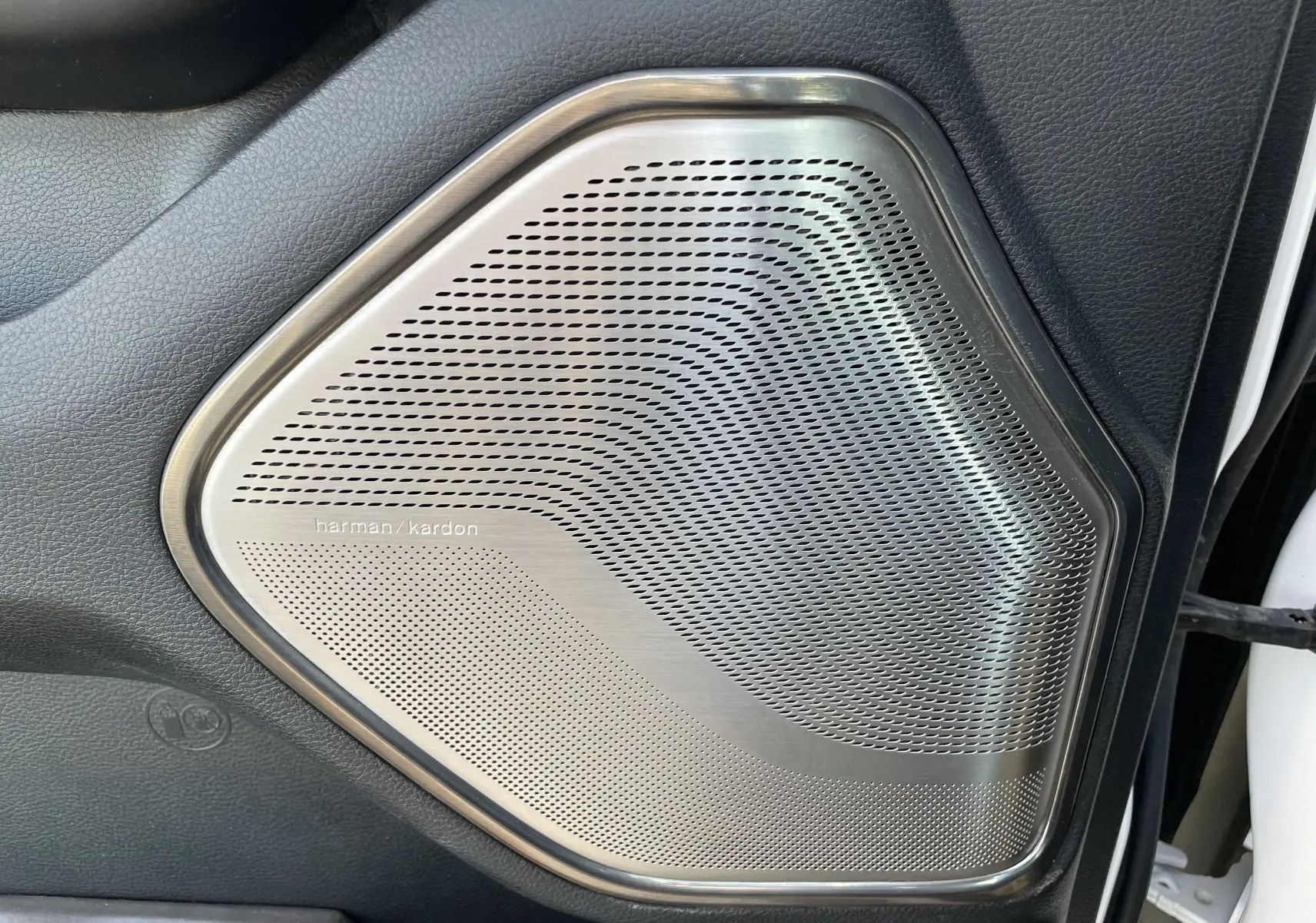 Gros plan sur le haut-parleur Harman Kardon intégré à la porte intérieure noire du Dodge RAM 1500 blanc nacré.
