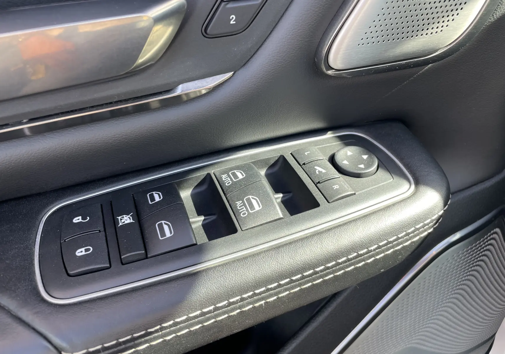 Gros plan sur les commandes de vitres et rétroviseurs côté conducteur du Dodge RAM 1500 Limited 2020 avec finition cuir noir.