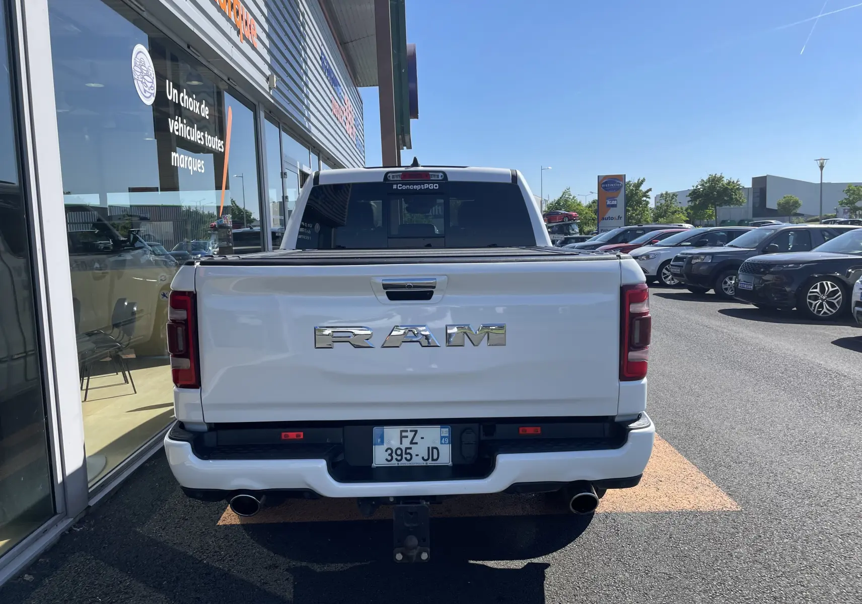Vue arrière d'un pick-up Dodge RAM 1500 blanc nacré avec logo chromé et double sortie d'échappement visible.