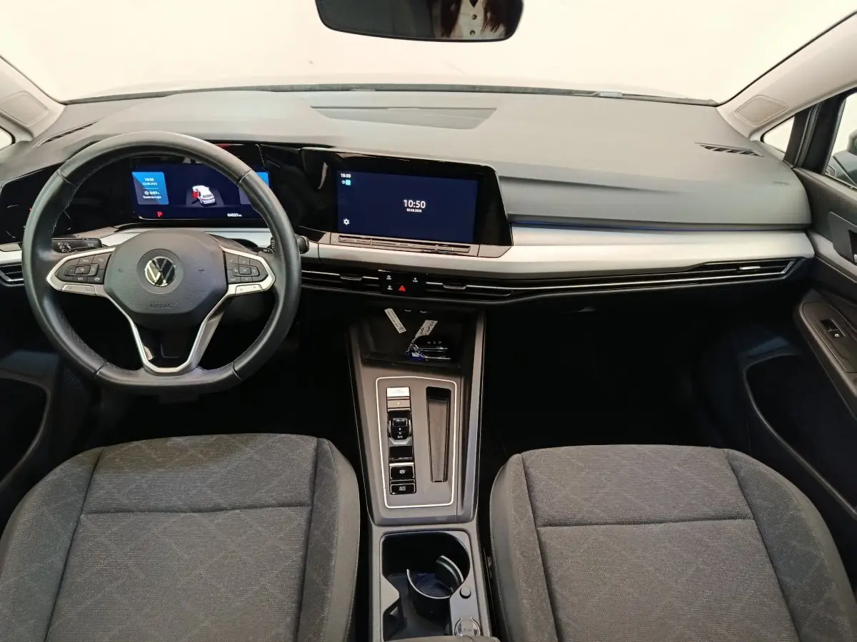Vue intérieure avant de la Volkswagen Golf gris foncé 2022, tableau de bord moderne avec écran tactile et volant cuir multifonctions.