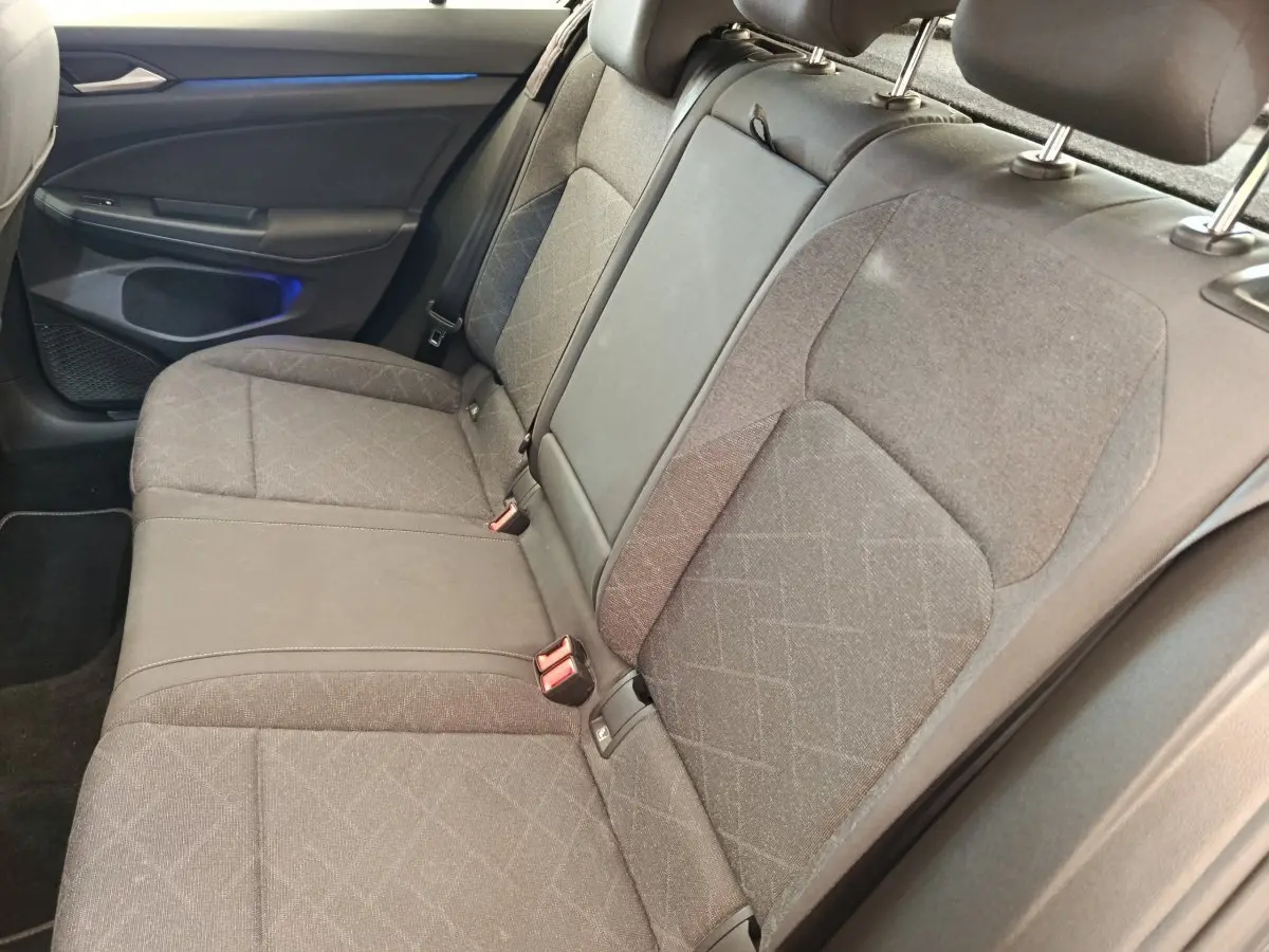Banquette arrière grise vue côté droit dans une Volkswagen Golf 2022, avec éclairage d'ambiance bleu sur la portière.