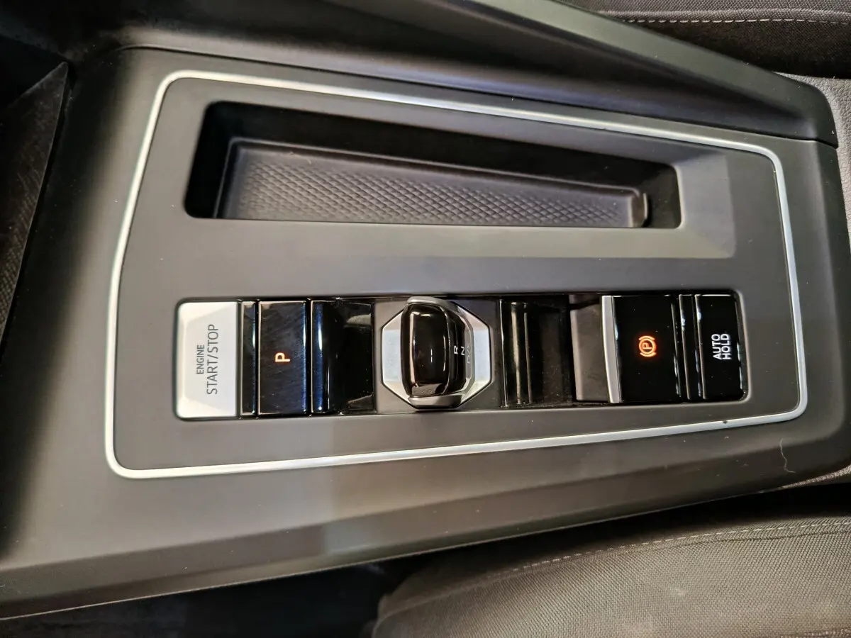 Gros plan sur la console centrale noire de la Volkswagen Golf 2022 avec levier de vitesses automatique et bouton start/stop.