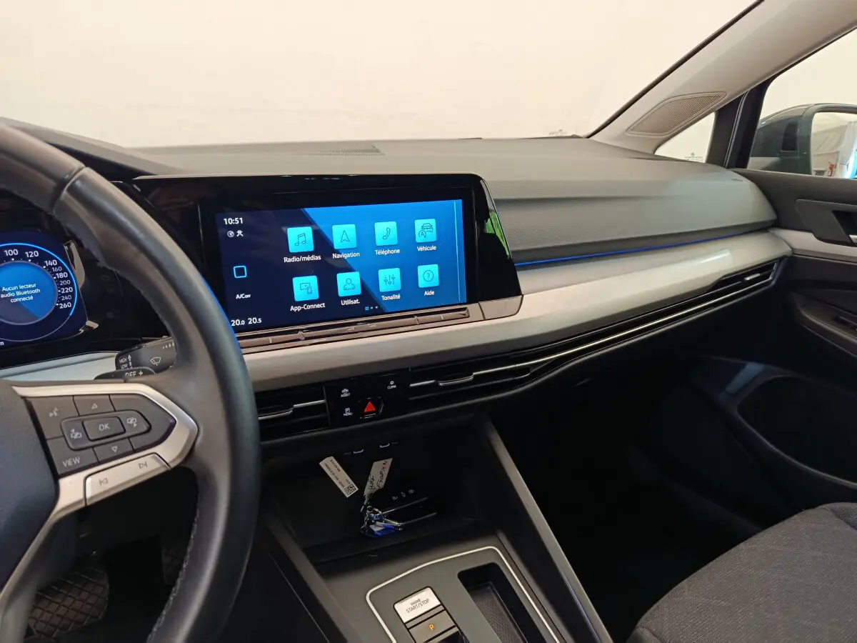 Intérieur de Volkswagen Golf 2022 gris foncé, vue tableau de bord avec écran tactile central et volant cuir multifonctions.