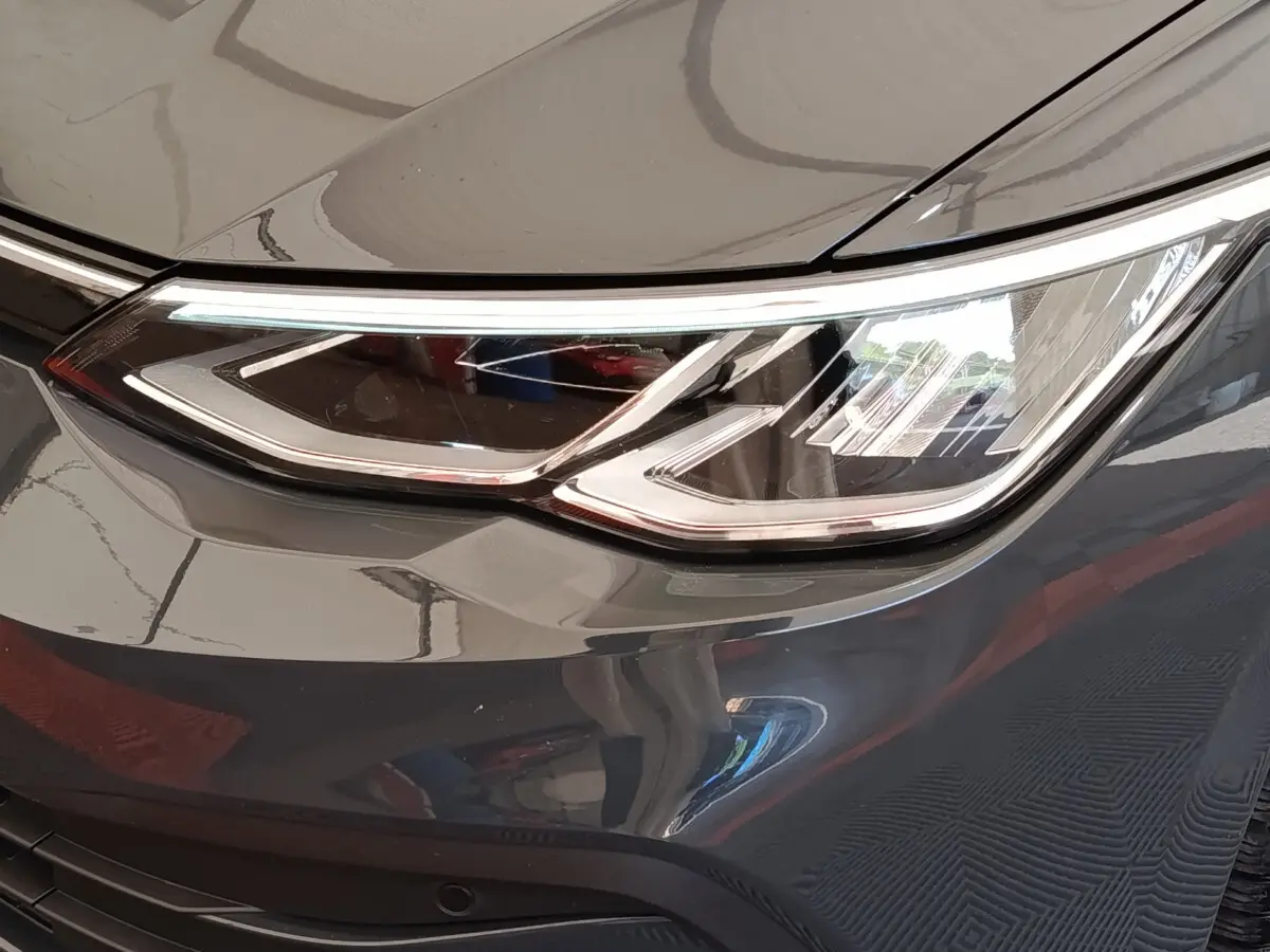Gros plan sur le phare avant droit d'une Volkswagen Golf gris foncé, mettant en valeur ses feux LED modernes.