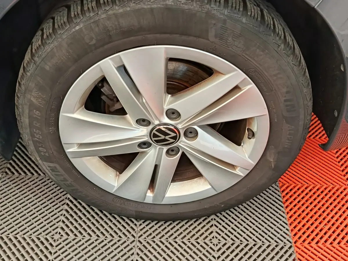 Gros plan sur la roue avant droite d'une Volkswagen Golf gris foncé avec jante alliage à cinq branches.