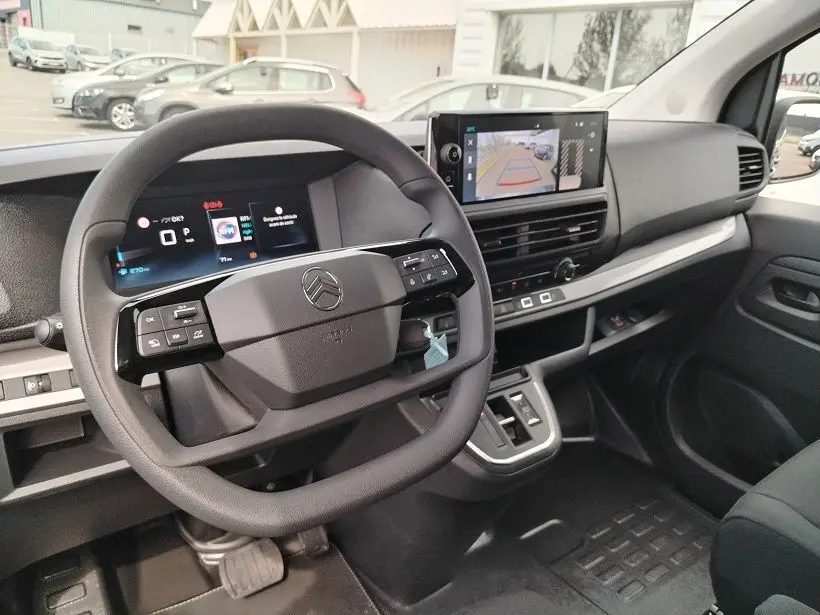 Vue intérieure côté conducteur du Citroën Jumpy Cabine Approfondie 2025, tableau de bord noir avec écran multimédia et volant multifonction.