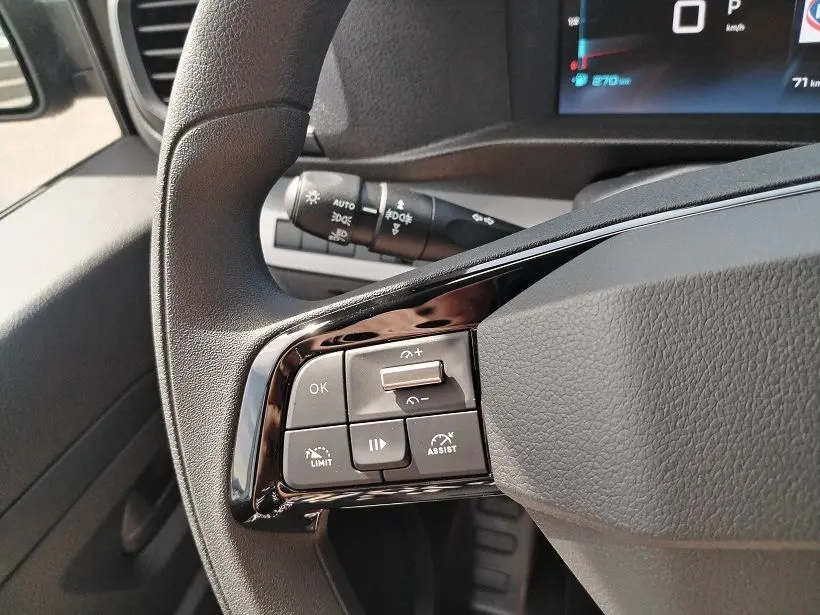 Gros plan sur les commandes gauche au volant du Citroën Jumpy Cabine Approfondie gris titane, avec tableau de bord numérique en arrière-plan.