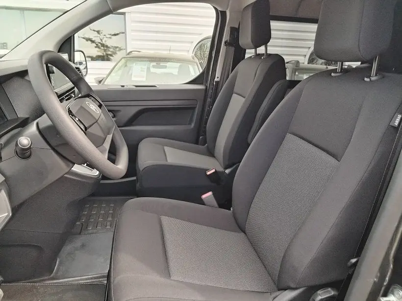 Vue intérieure côté conducteur du Citroën Jumpy Cabine Approfondie 2025, sièges noirs avec accoudoirs et volant multifonction.