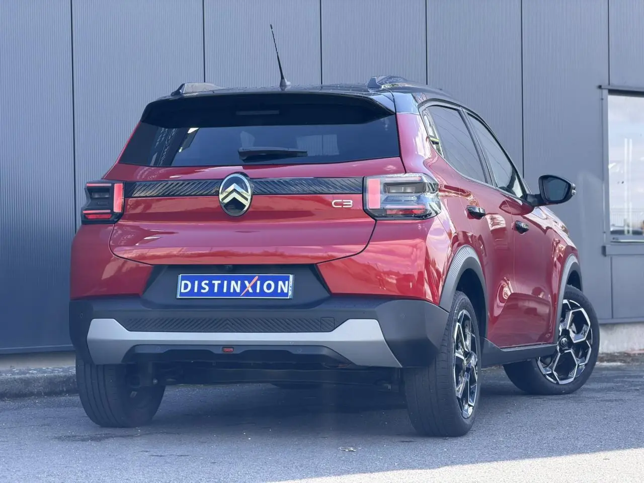 Vue 3/4 arrière droite d'une Citroën C3 2025 Rouge Elixir avec toit noir et jantes alliage distinctives.