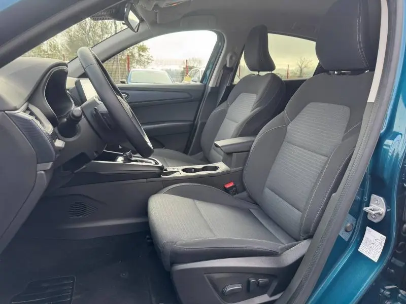 Vue intérieure côté conducteur du Renault Arkana 2025 bleu Zanzibar, montrant les sièges avant et la console centrale.