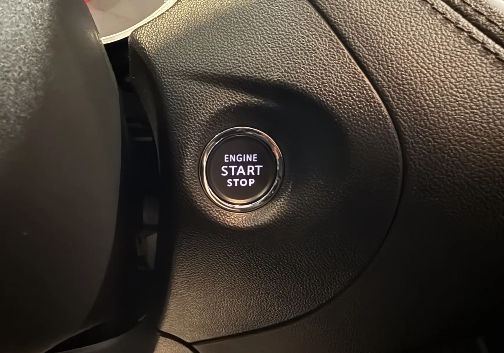 Bouton start/stop moteur éclairé en blanc sur fond noir, intégré dans le tableau de bord en cuir noir d'un Opel Grandland X hybride.