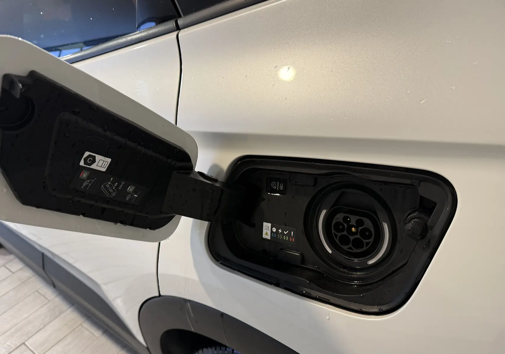 Prise de recharge ouverte côté gauche d’un Opel Grandland X blanc hybride rechargeable, vue rapprochée sur le port de charge.