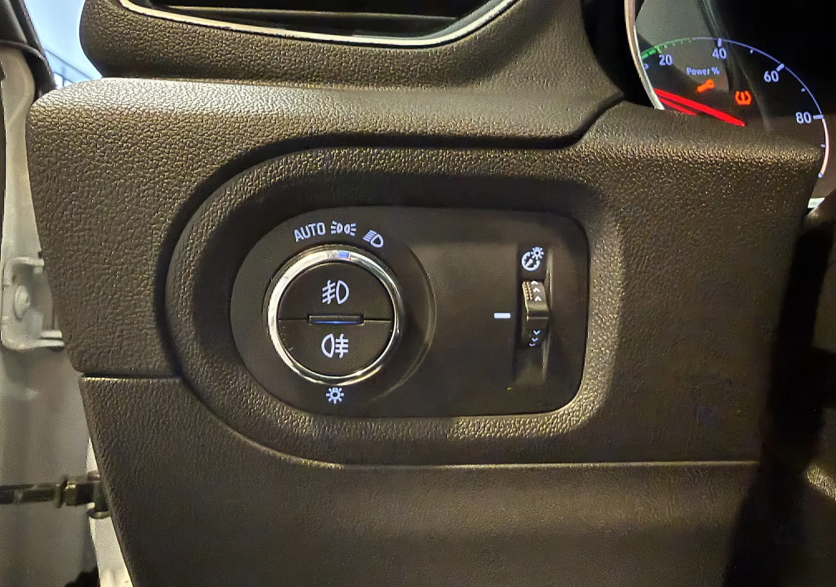 Gros plan sur le panneau de commandes d'éclairage noir à gauche du tableau de bord de l'Opel Grandland X blanc.
