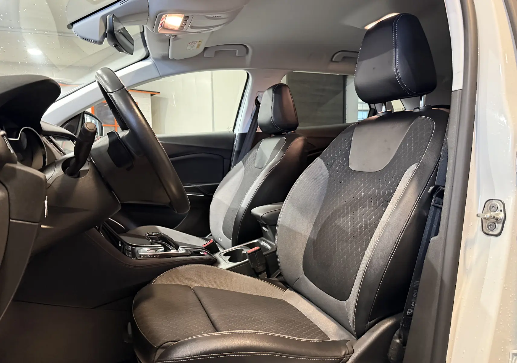 Vue intérieure côté conducteur de l’Opel Grandland X blanc, sièges avant en cuir et tissu noir avec coutures contrastées.