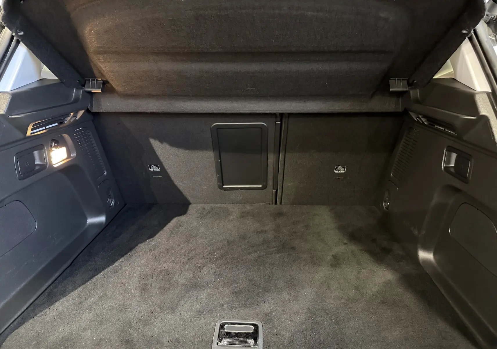 Coffre ouvert de l’Opel Grandland X blanc, vue intérieure montrant un espace de chargement propre et bien éclairé.