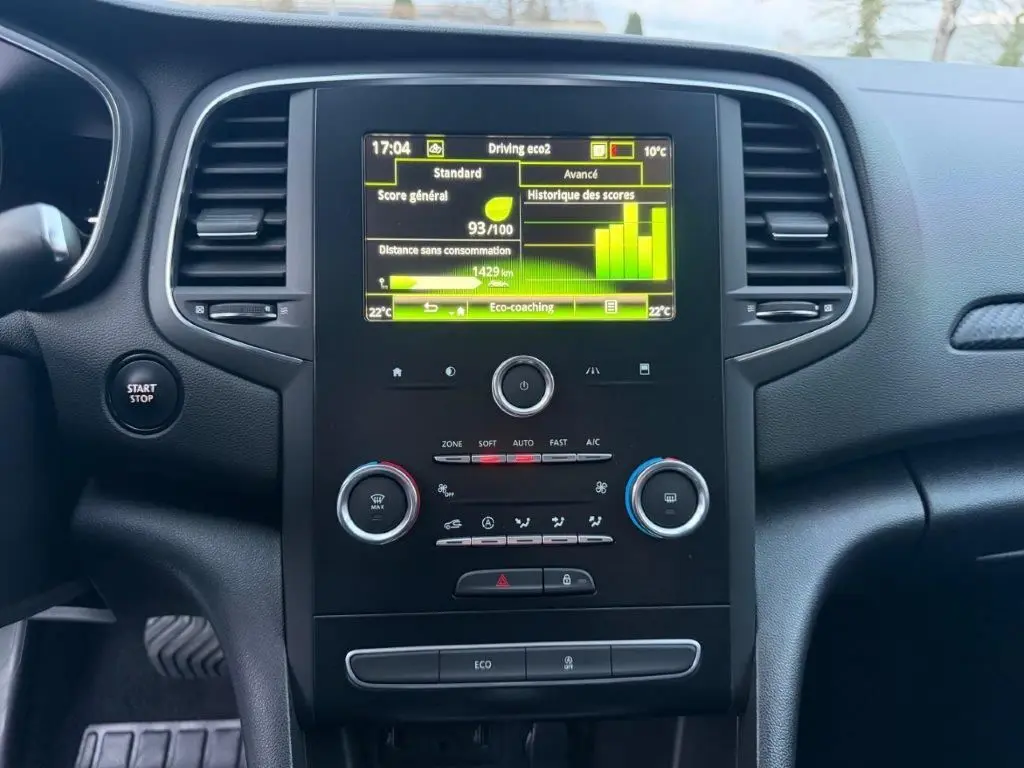 Vue rapprochée du tableau de bord de la Renault Mégane Business, avec écran tactile et commandes de climatisation.