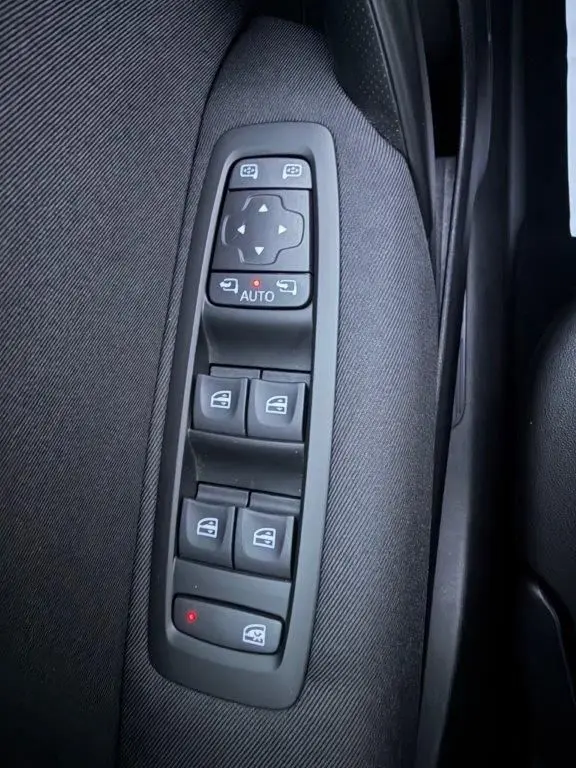 Gros plan sur les commandes de lève-vitres et rétroviseurs électriques sur la porte côté gauche d’une Renault Mégane Business gris alu.