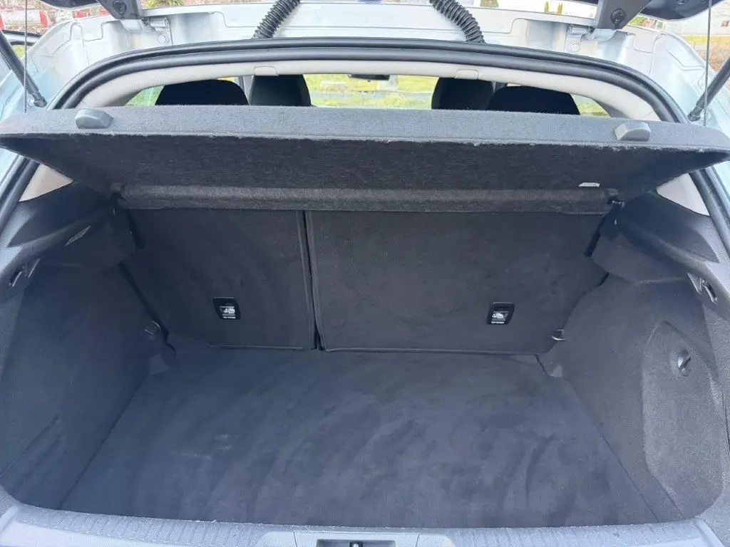 Coffre ouvert vu de l'arrière d'une Renault Mégane Business gris alu, montrant un espace de chargement propre et spacieux.