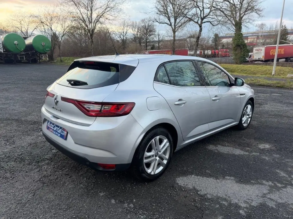 Vue 3/4 arrière droite d'une Renault Mégane Business gris alu avec feux arrière LED et jantes alliage sur parking extérieur.