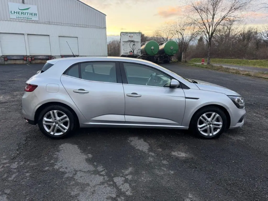 Profil côté gauche d'une Renault Mégane Business gris alu, avec jantes alliage et lignes épurées visibles.