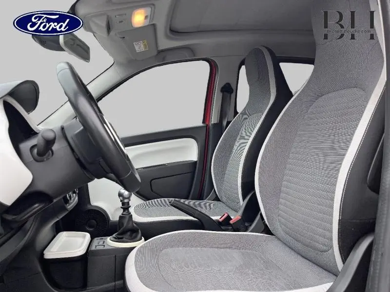 Vue intérieure côté conducteur de la Renault Twingo rouge Flamme 2019 avec sièges tissu gris et toit ouvrant visible.