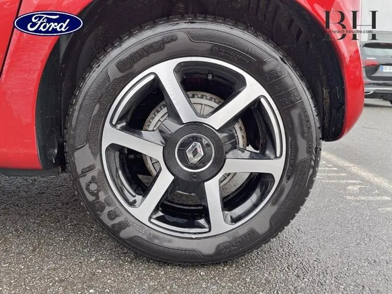 Gros plan sur la jante alu noire et argentée avec logo Renault, roue avant droite d'une Renault Twingo Rouge Flamme.