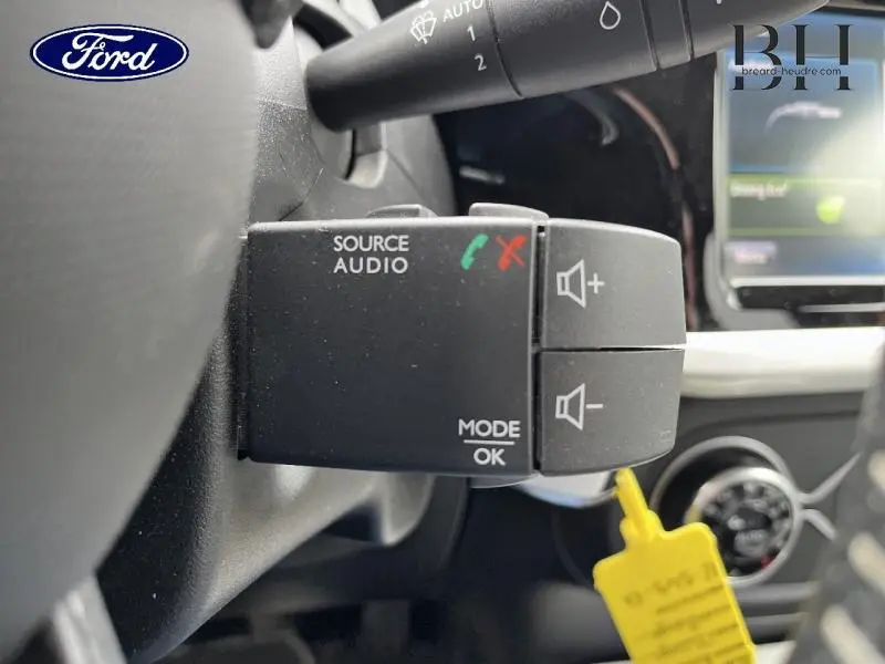 Commande audio au volant côté gauche d'une Renault Twingo rouge Flamme avec toit ouvrant, vue intérieure rapprochée.