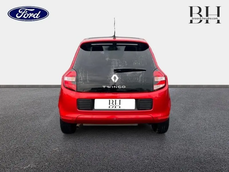 Vue arrière d'une Renault Twingo rouge flamme avec lunette arrière teintée et logo central visible.