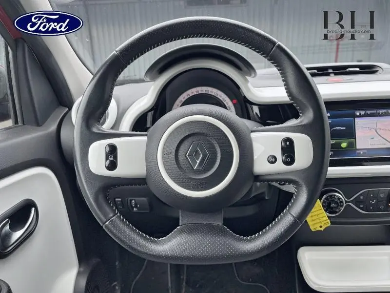 Vue intérieure centrée sur le volant noir et blanc de la Renault Twingo 2019 avec tableau de bord et écran tactile visibles.