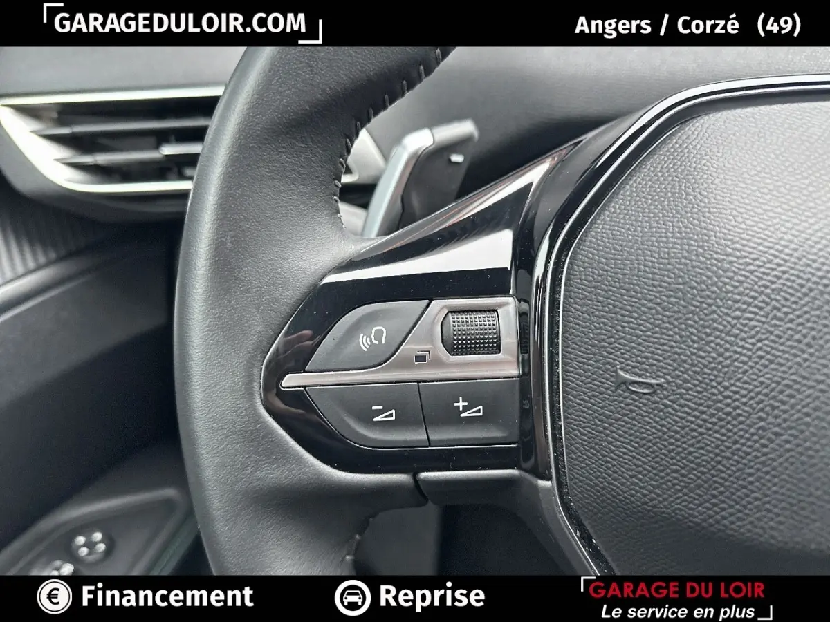 Gros plan sur le volant cuir noir du Peugeot 3008 blanc, avec commandes audio intégrées visibles à gauche.