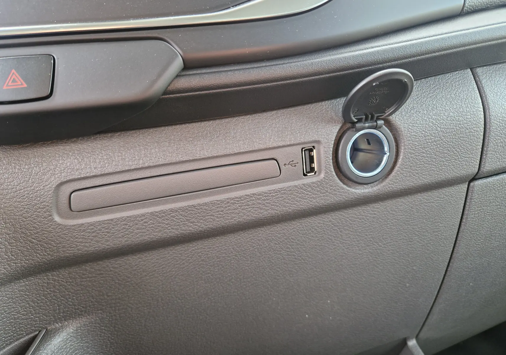 Détail de la console intérieure grise du Ford Transit Chassis Cabine 2026, avec prise USB et allume-cigare ouvert.