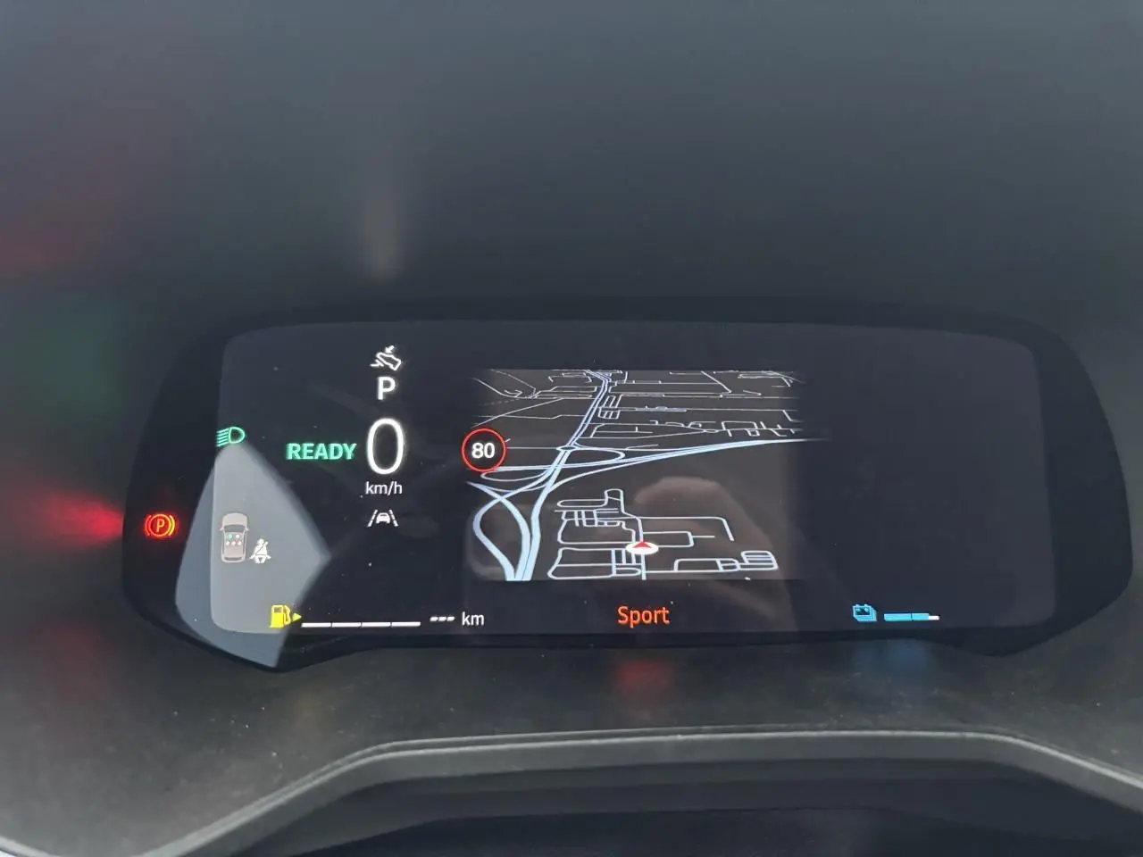 Tableau de bord numérique de Renault Clio 2025 affichant la navigation et mode Sport, vu de face en intérieur.
