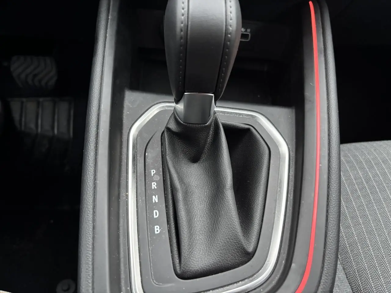 Le levier de vitesses automatique noir de la Renault Clio V hybride, avec surpiqûres et contour argenté, vu de dessus.